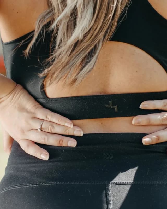 A woman holding her lower back with both hands