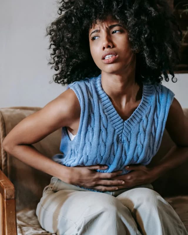 A woman sitting in a chair holding her stomach in pain