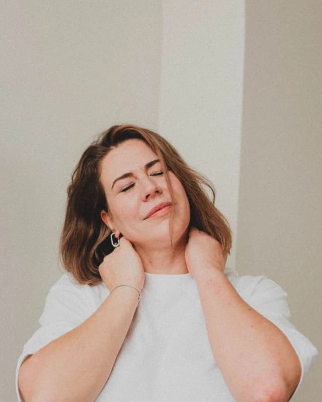 A woman with her eyes closed holding her neck