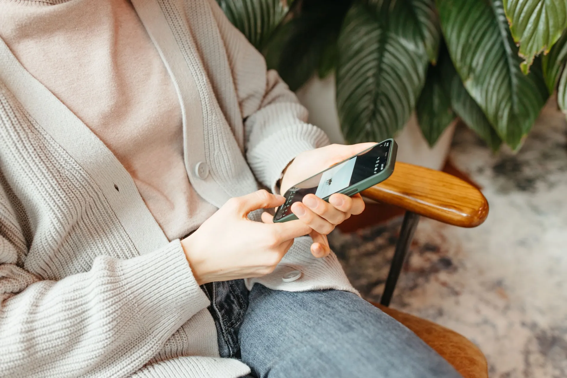 Hands holding a phone, resting in a chair.