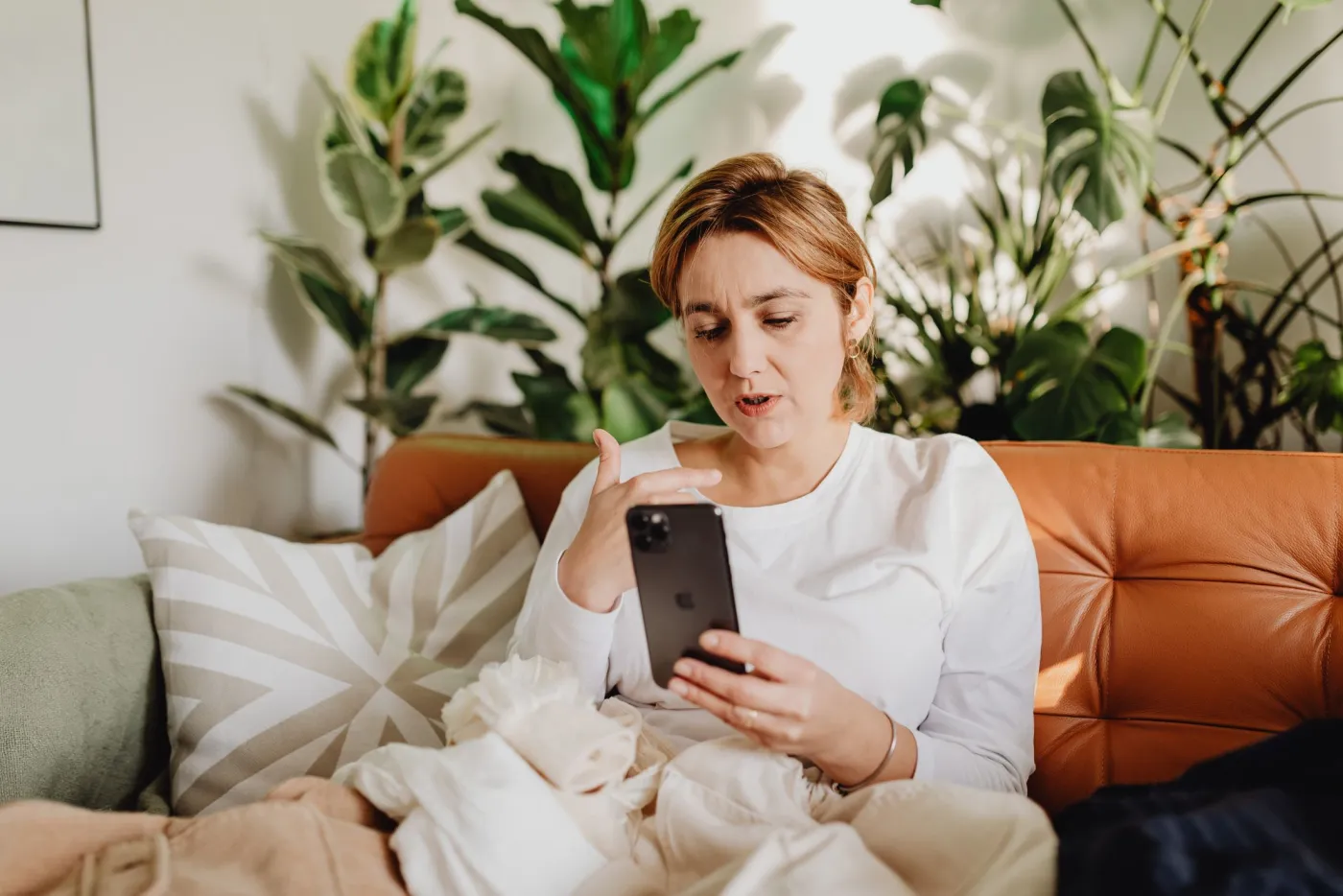 A woman on a sofa talking to her phone.
