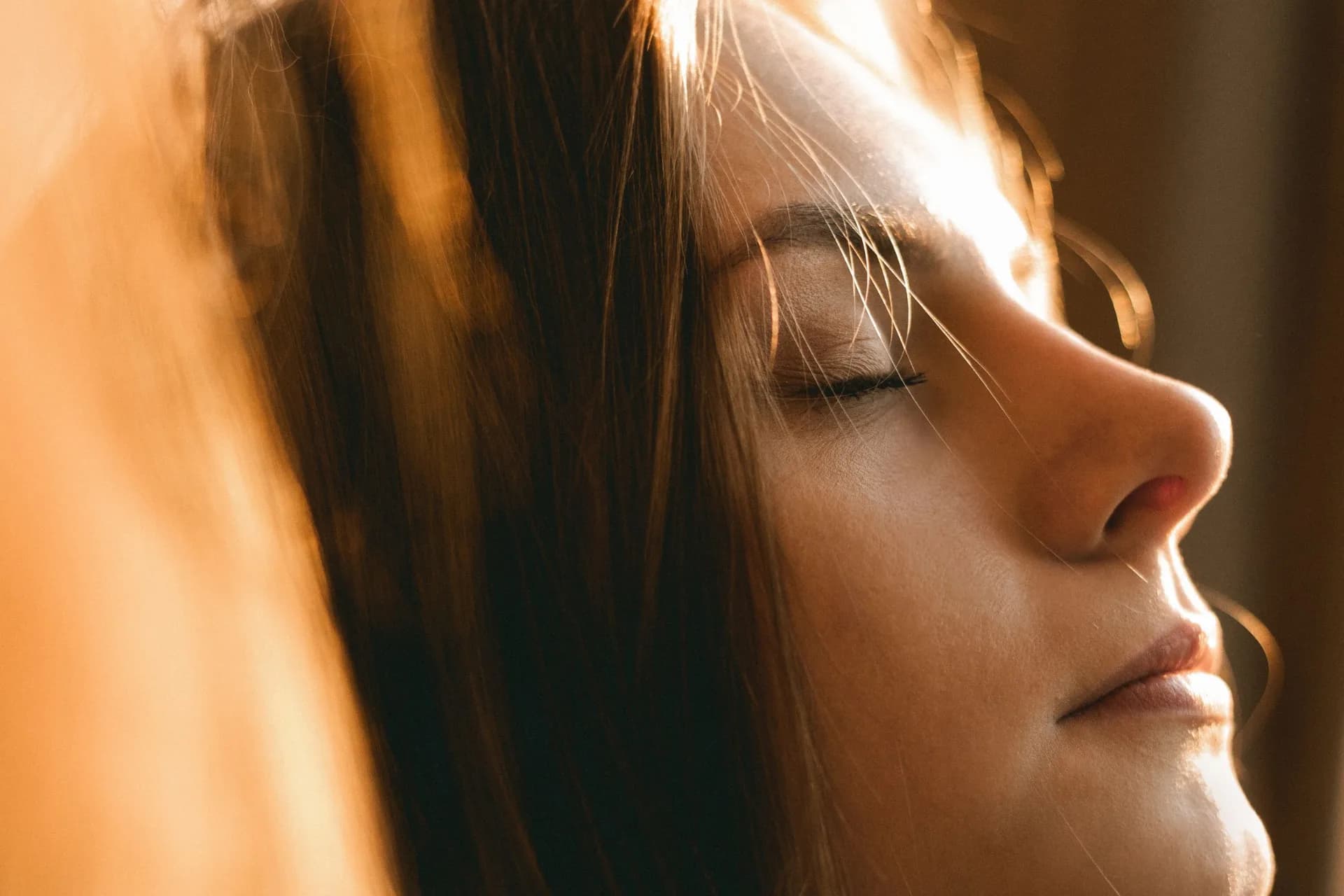 A woman with her eyes closed in warm evening light.