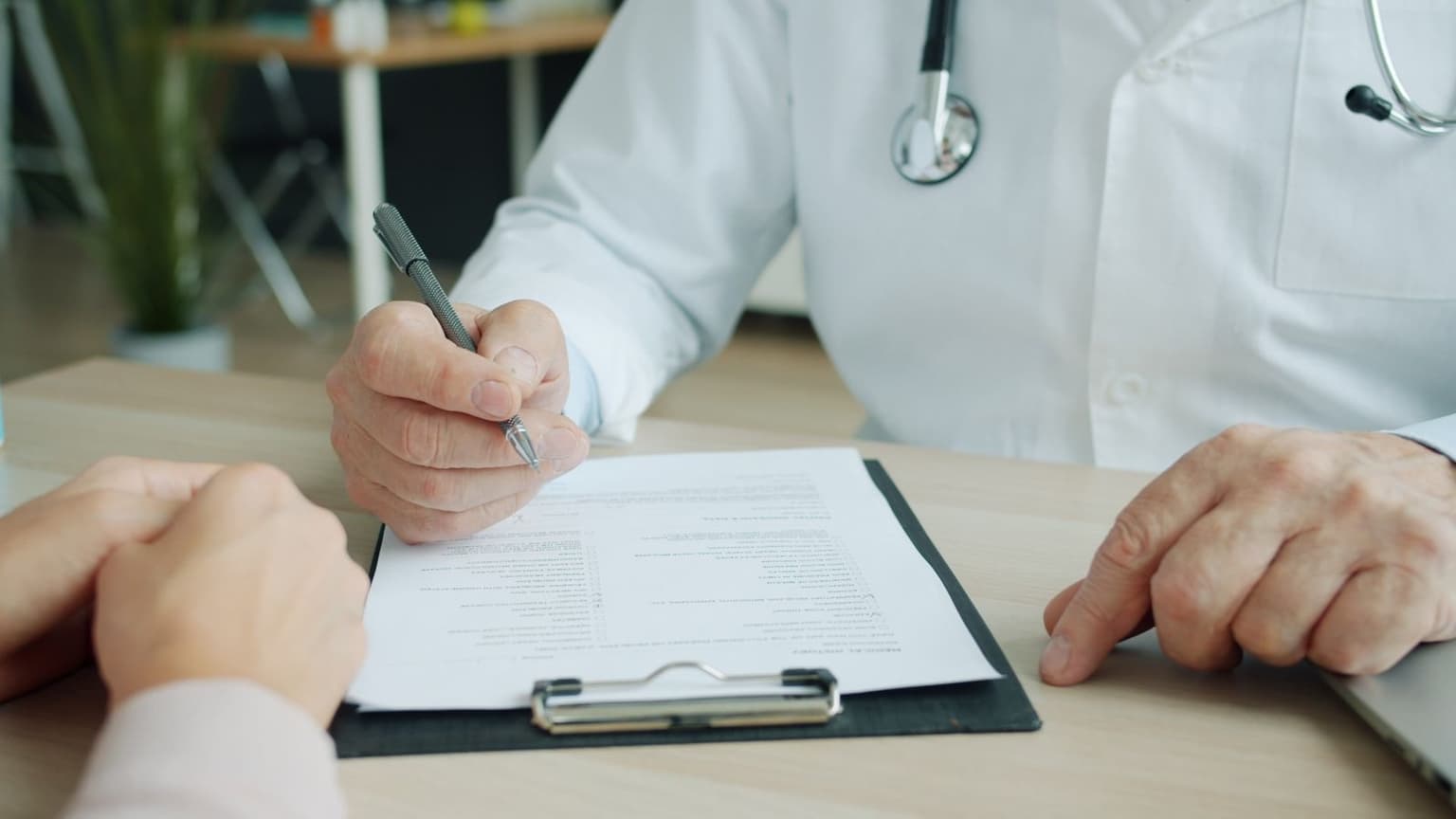 A doctor and patient sitting at a desk together, reviewing printed medical documents