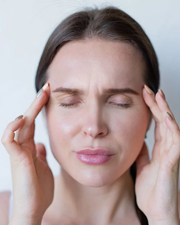 A woman pressing her fingers to her temples with a headache