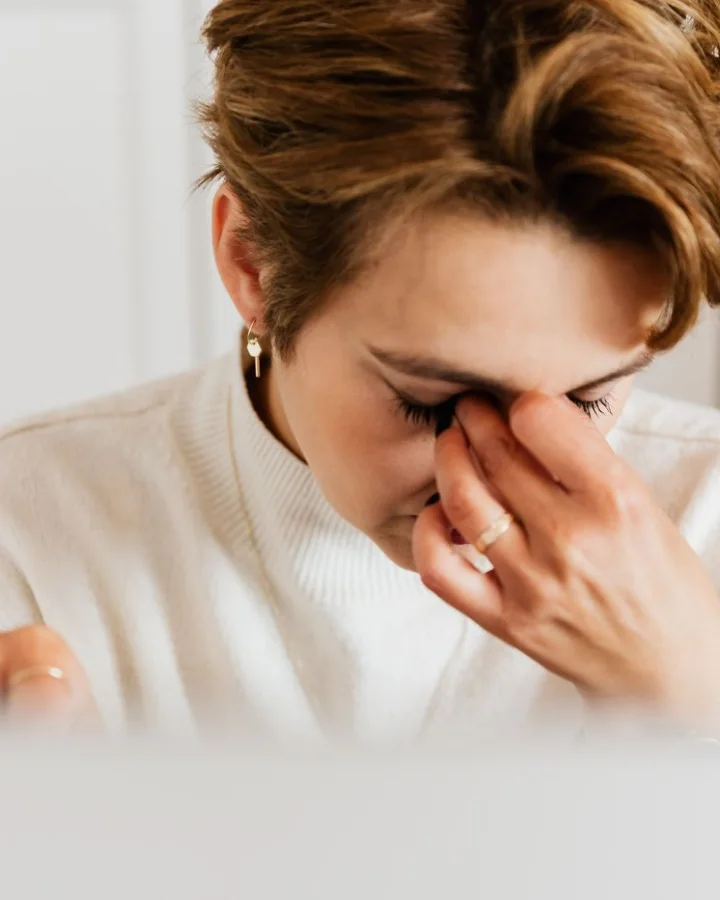 A tired woman pinching the bridge of her nose